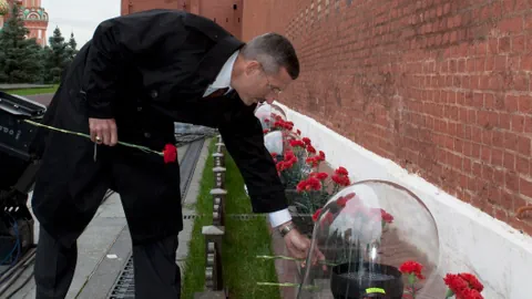 Menschen legen am Grab Blumen nieder.