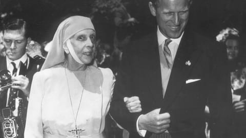 schwarzweiss Foto, links eine Nonne in weissem Gewand, rechts ein junger Mann im Anzug, sie bei ihm eingehakt.