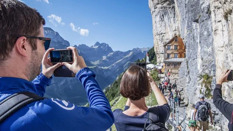 Menschen fotografieren ein Gasthaus am Berg.