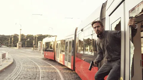 Ein Mann schaut aus einem Tram, eine Pistole in der Hand.