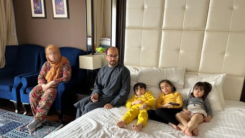 Familie mit drei kleinen Kindern in Hotelzimmer.