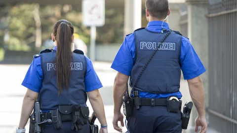 Eine Polizistin und ein Polizist von hinten fotografiert.