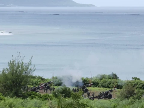 Artilleriegeschütze am Meer mit Rauchentwicklung.