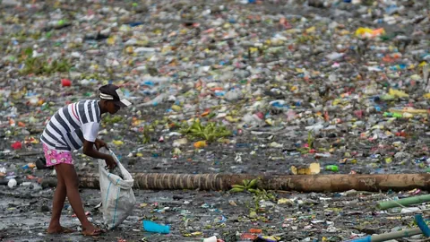 Eine Person sammelt Plastik ein auf den Philippinen.