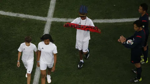 Ein Kind mit einem roten Transparenta auf einem Fussballplatz.