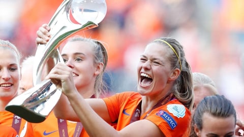 Frauen in oranegn Trikots mit einem Pokal