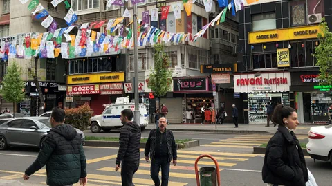 Belebte Strasse mit Autos, einem Fussgängerstreifen, Passanten und Läden