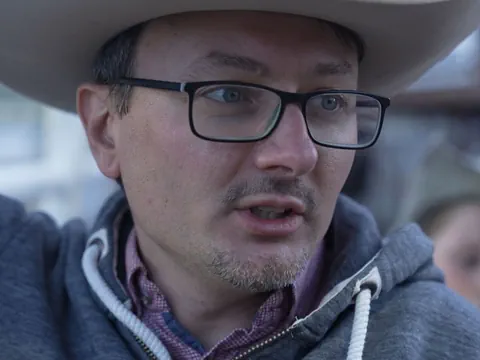 Portraitaufnahme von Daniel Jakli. Er trägt eine Brille und ein Cowboy-Hut.