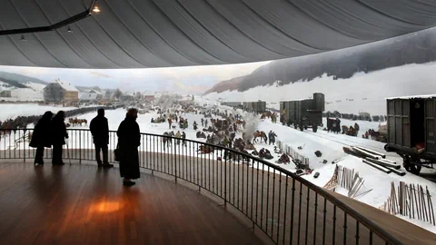 Besuchende schauen auf eine gemalte Winterlandschaft.