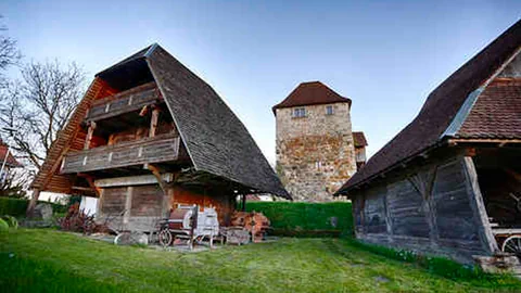 Zwei Holzspeicher, dazwischen im Hintergrund ein Burgturm aus Stein gebaut.