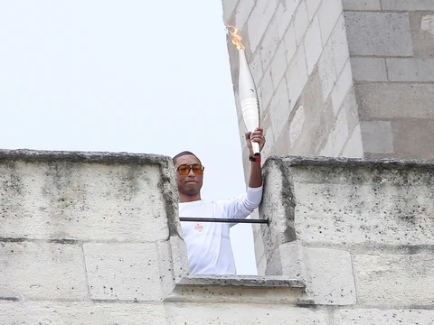 Person hält Fackel auf einer Steinmauer.