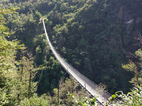 Eine Hängebrücke für Fussgänger erstreckt sich über ein Tal.