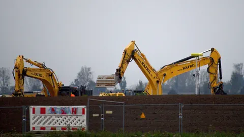 Zwei gelbe Bagger auf Baustelle bei bewölktem Himmel.