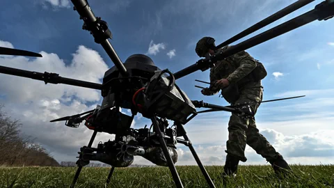 Drohne und Soldat auf einem Feld.