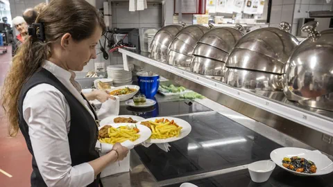 Kellnerin stellt Teller mit Pommes Frites in der Küche bereit.