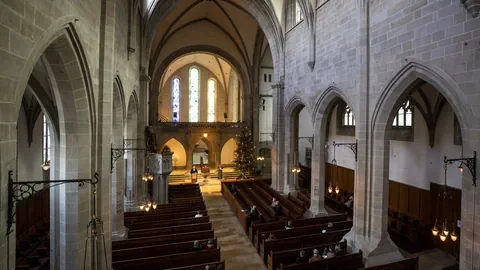 Innenraum der Fraumünster-Kirche mit Bänken und Buntglasfenstern.