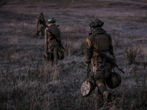 Drei Soldaten mit Ausrüstung auf einem Feld.