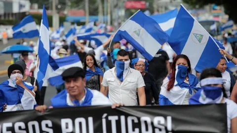 Menschen bei einer Demonstration in Managua mit Flaggen und Transparenten.