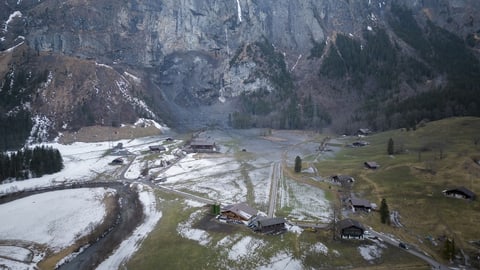 Das herabgestürzte Felsgestein liegt knapp neben ein bis zwei Häusern auf einer Wiese.