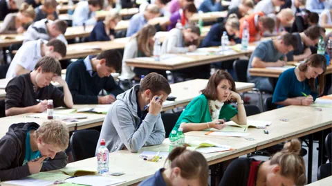 Studierende denken in einem Vorlesungssaal nach.