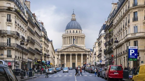 Eine Strasse in Frankreich mit vielen Autos und einem imposanten Gebäude.