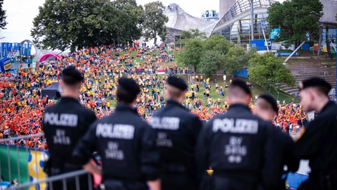 Polizisten beobachten eine grosse Menschenmenge in einer EM-Fanzone im Freien.