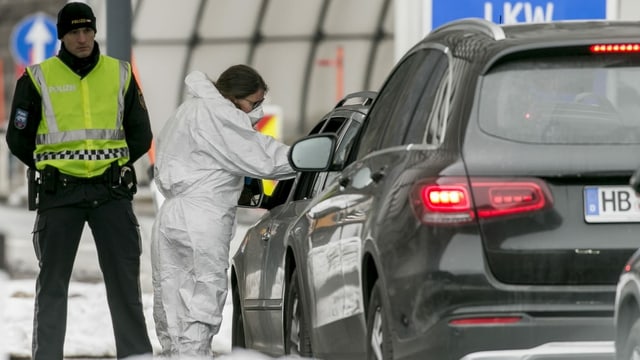 Eine Ärztin kontrolliert die Temperatur eines Autofahrers an einem Grenzübergang. 