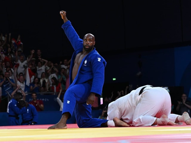 Judo-Wettkampf mit Judokämpfer im blauen Gi, der feiert.