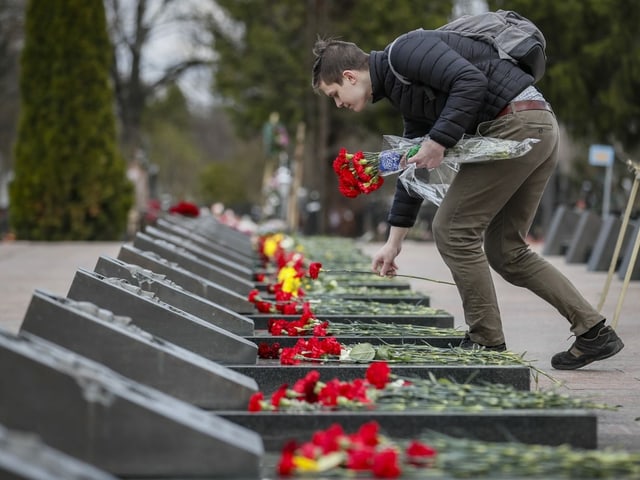 Ein Mann legt Blumen auf Gräber