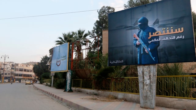 Symbolbild: Eine Strasse ohne Vekehr, am Rand hängt ein grosses Plakat mit einem maskierten Bewaffneten und Kampfflugzeugen im Hintergrund.