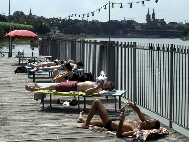 Menschen sonnen sich an der Aare in Bern