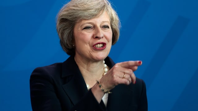 Theresa May zeigt mit dem Finger auf etwas.