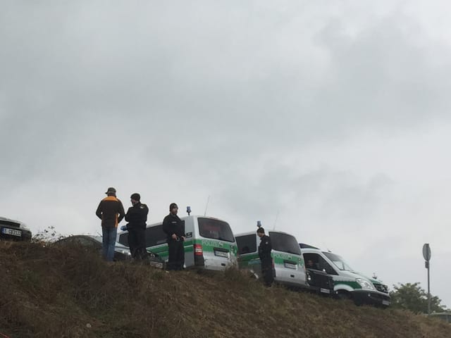 Polizisten und Polizeiautos auf einer Kuppe.