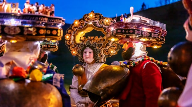 Mehrere verkleidete Menschen mit Hauben und Masken im Morgenblau.