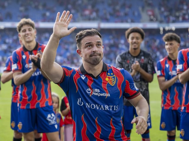 Fussballspieler im Streifen-Trikot winkt, umgeben von applaudierenden Teamkollegen.