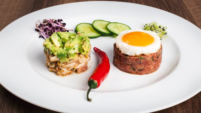 «Felchenfilet Tatar» mit «Avocado Tatar» und «Tatar von Rindshuft» verziehrt mit Gurtenscheiben, Salat und eine Chilischote