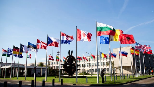 Nato-Hauptquartier in Brüssel, im Vordergrund sind die Fahnen der Mitgliedsstaaten.