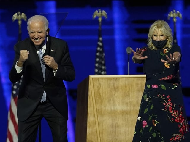 Joe und Jill Biden treten in Siegespose vor die Medien.