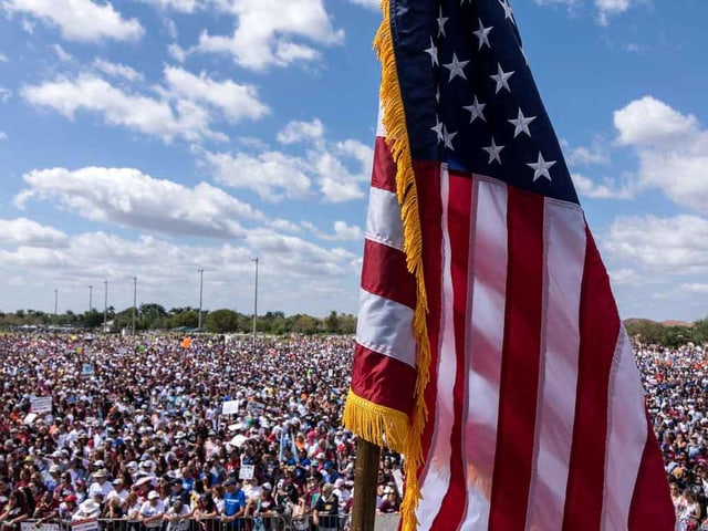 Massen protestieren, im Vordergrund die US-Flagge.