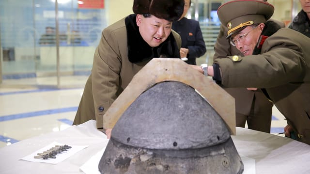 Kim Jong Un begutachtet zusammen mit einem Militär einen Raketensprengkopf auf einem Tisch