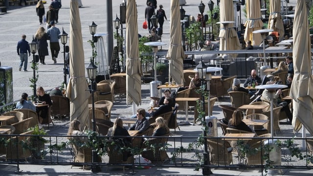 People outside in chairs in front of a cafe