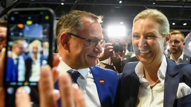 Tino Chrupalla und Alice Weidel werden von einem Handy fotografiert.