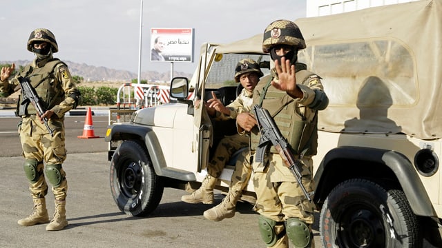 Bewaffnete und vermummte Soldaten in Tarnuniformen und schussicheren Westen vor einem Militärjeep, im Hintergrund ein Plakat mit dem Konterfei Al Sisis.