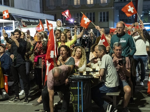 Menschenmenge mit Schweizer Flaggen bei Nachtveranstaltung