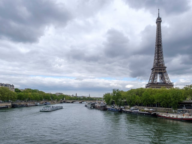 Seine-Fluss mit dem Eiffelturm im Hintergrund an einem bewölkten Tag.