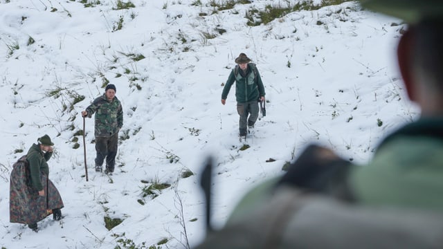 Drei Jäger laufen im Schnee