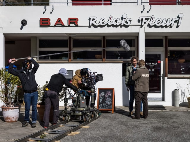 Schauspielende vor einer Bar am Tag,