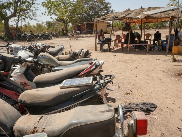 Motorräder, im Hintergrund Menschen in Unterstand