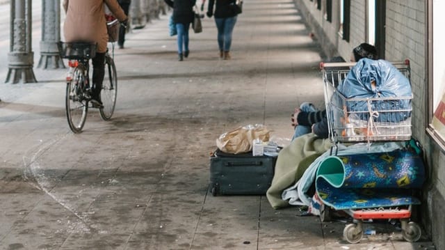 Unterführung, man sieht am Rand einen Einkaufskorb mit vielen Ustensilien wie Taschen und Matte, hinten ist ein Mensch.