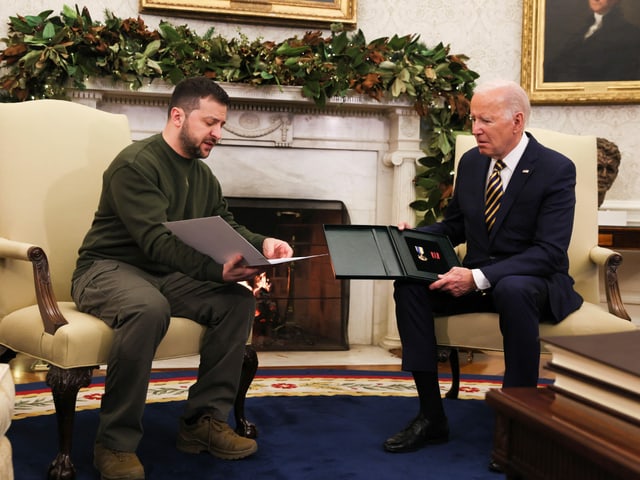 Selenski und Biden schauen in eine Unterlagenmappe.